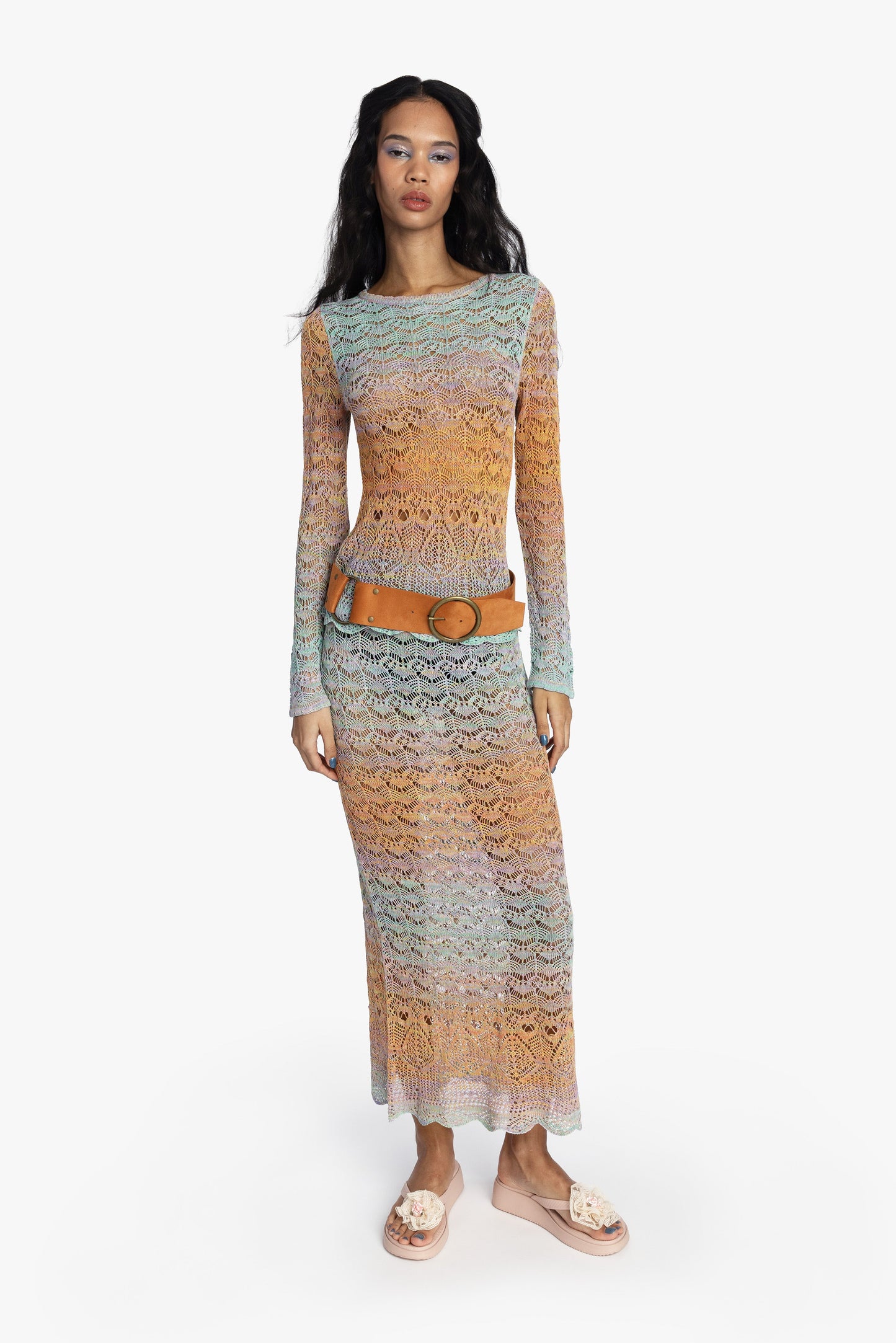 Women wearing a colorful gradient crochet outfit with a tan suede belt on a white background.