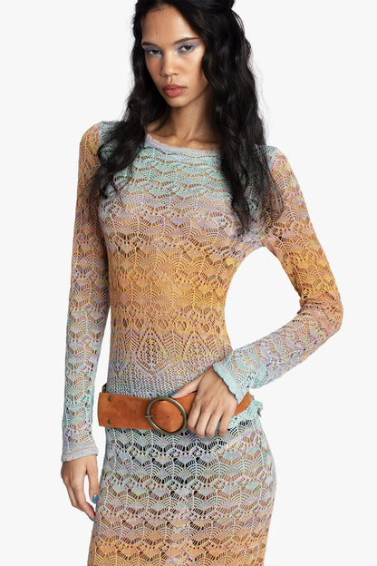 Woman wearing a long-sleeve crochet top with a gradient color pattern on a white background.
