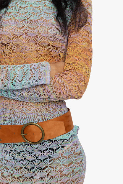 Detail view of  the crochet detail of a gradient long sleeve top, skirt, and belt worn by a women.