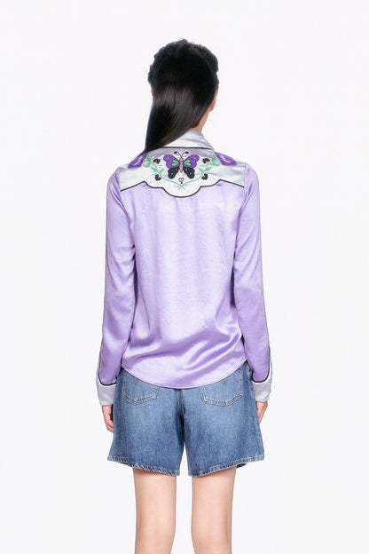 Woman wearing a Purple Boudoir Satin wavy Floral Embroidered on back shoulders and denim shorts.