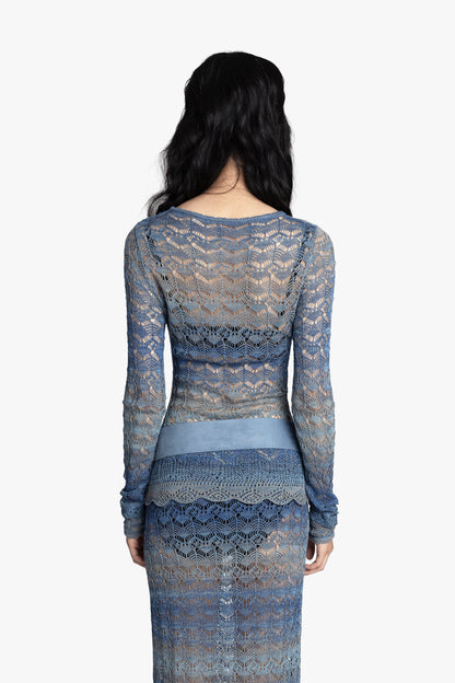 Back view of a woman wearing a blue crochet top and matching skirt with a blue belt on a white background.