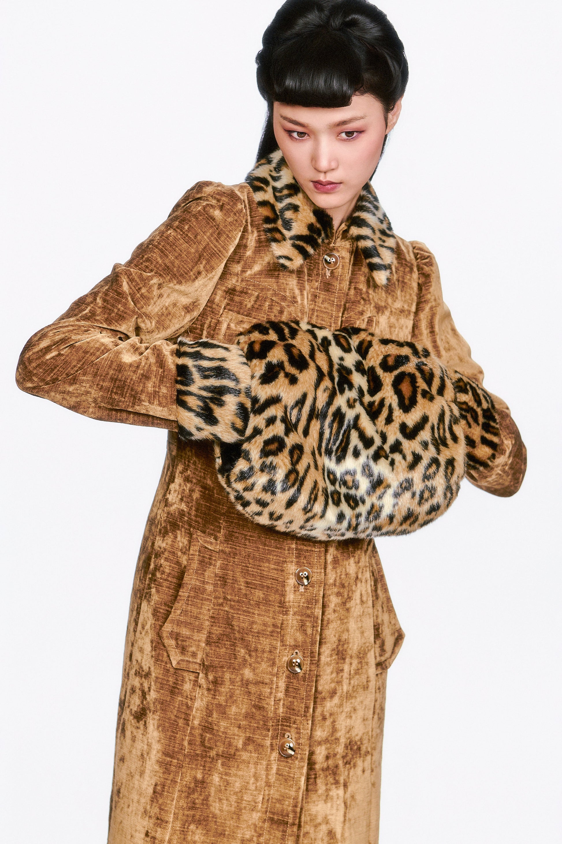 Person wearing a brown coat with Faux Leopard Muff accents.