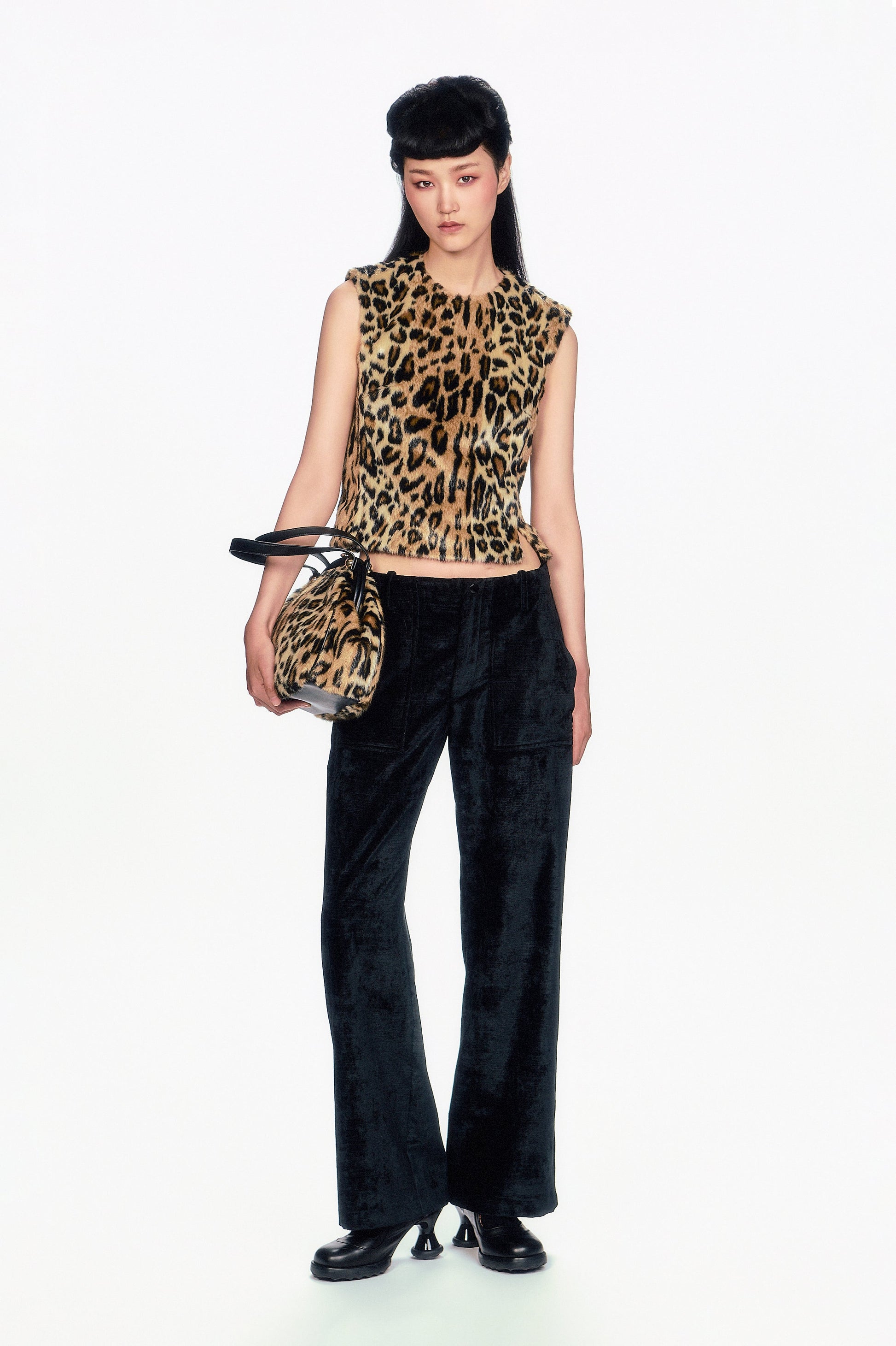 Woman wearing a Faux Leopard Sleeveless Top and black pants holding a matching handbag