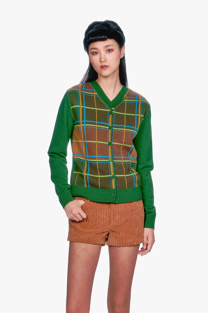 Woman wearing a Long Sleeves Plaid Cardigan - Leaf Green top and beige pleated skirt.