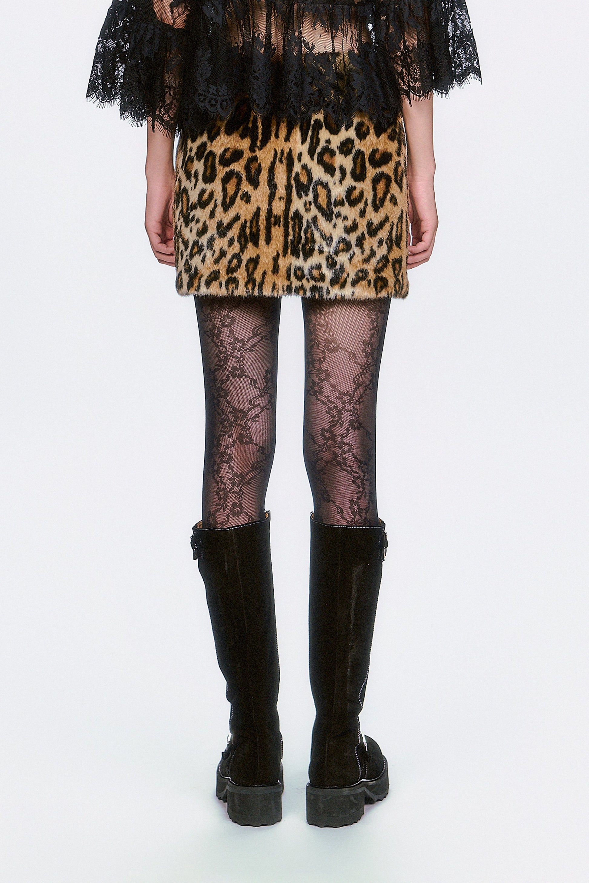 Woman wearing a Faux Leopard Mini Skirt, black lace top, and black knee-high boots. 