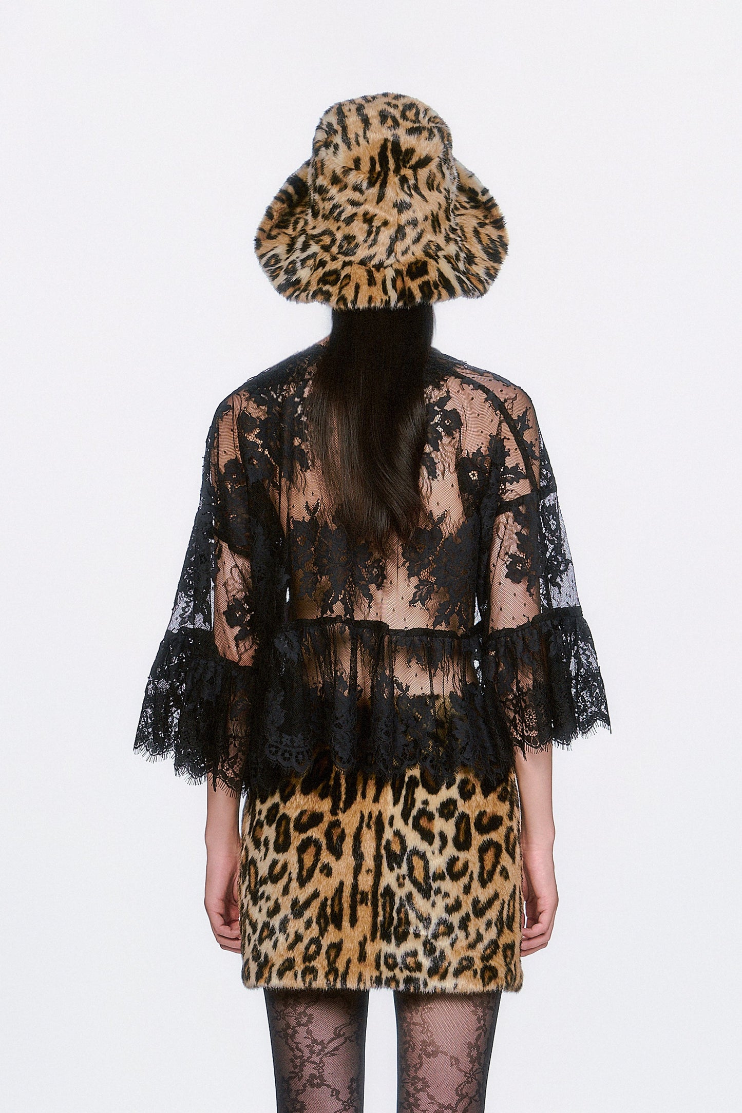 Person wearing a black floral design on see-thru lace top, with a faux leopard print skirt.