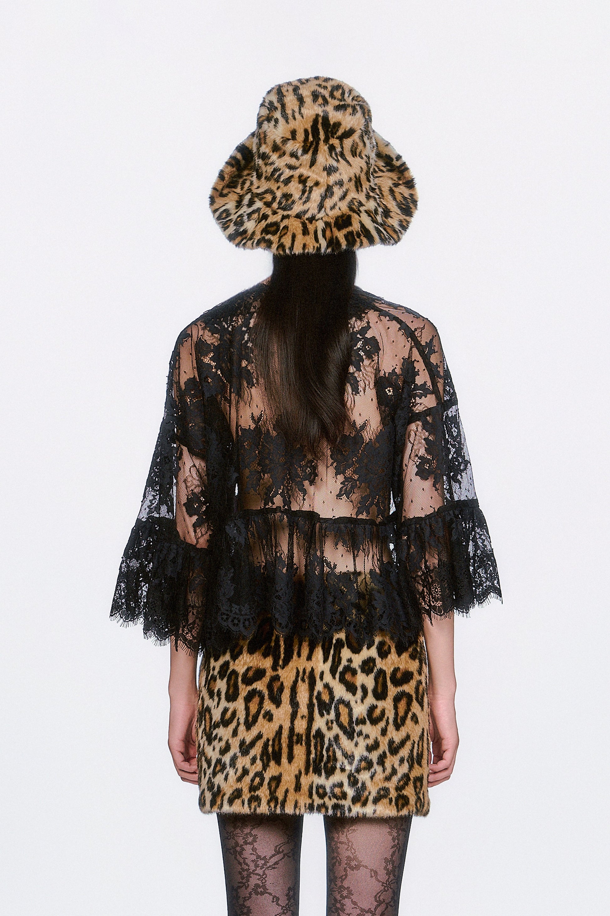 Person wearing a black floral design on see-thru lace top, with a faux leopard print skirt.