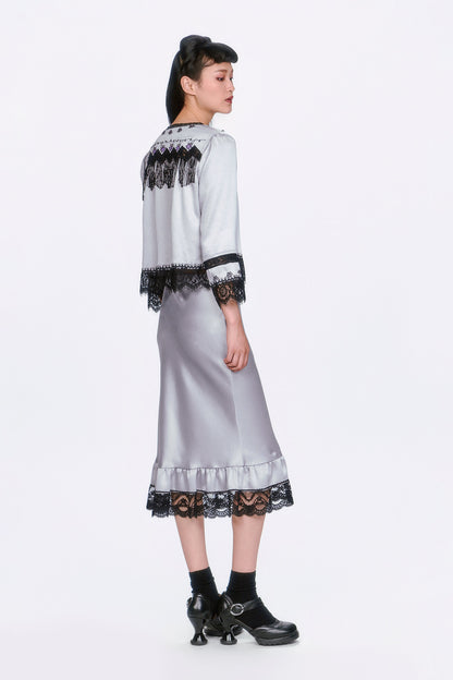 Woman wearing Boudoir Satin Beaded Fringe Bed Silver Jacket and skirt with black lace details.