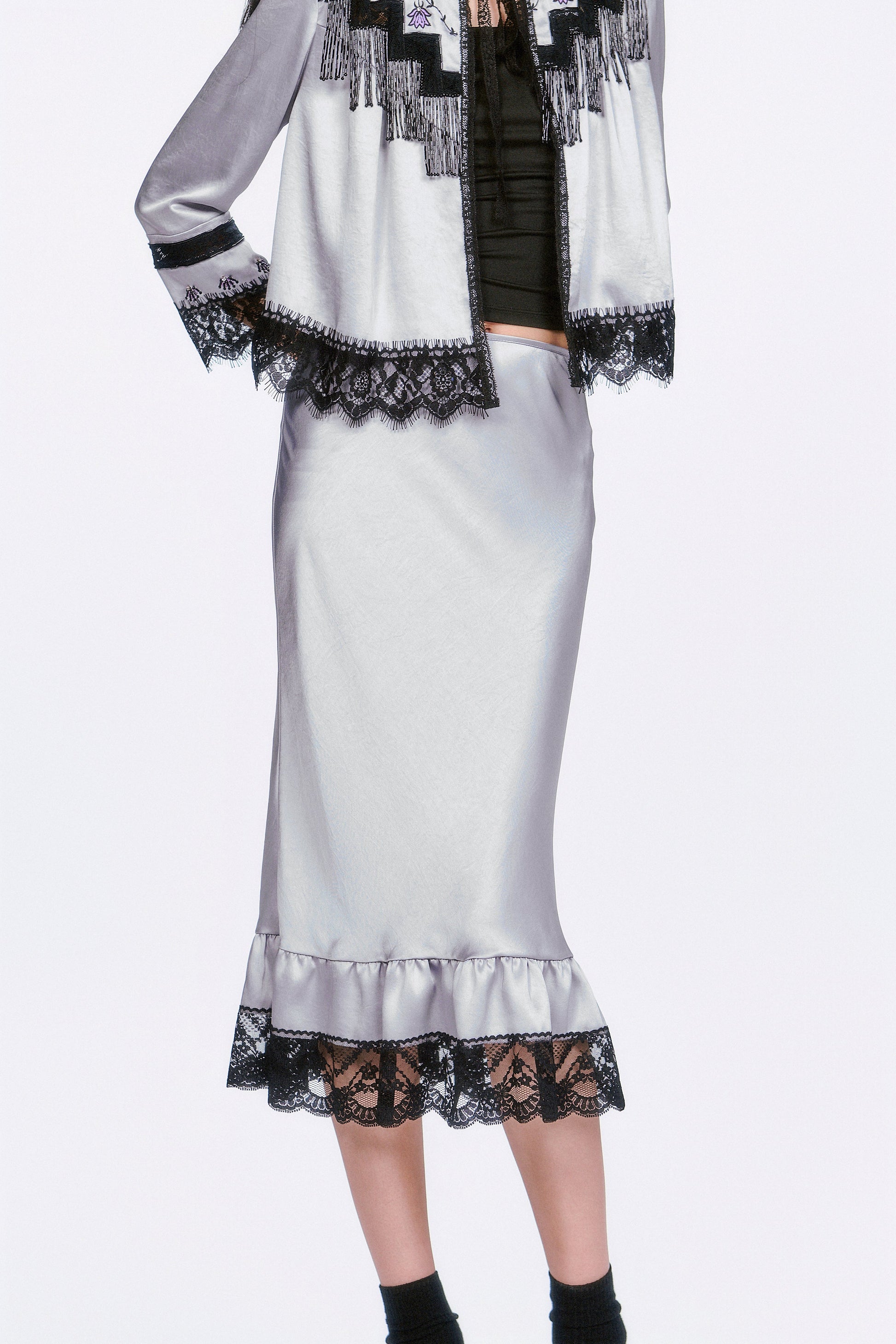 Boudoir Satin Beaded Fringe Bed Silver Jacket paired with a silver skirt, black socks and shoes.