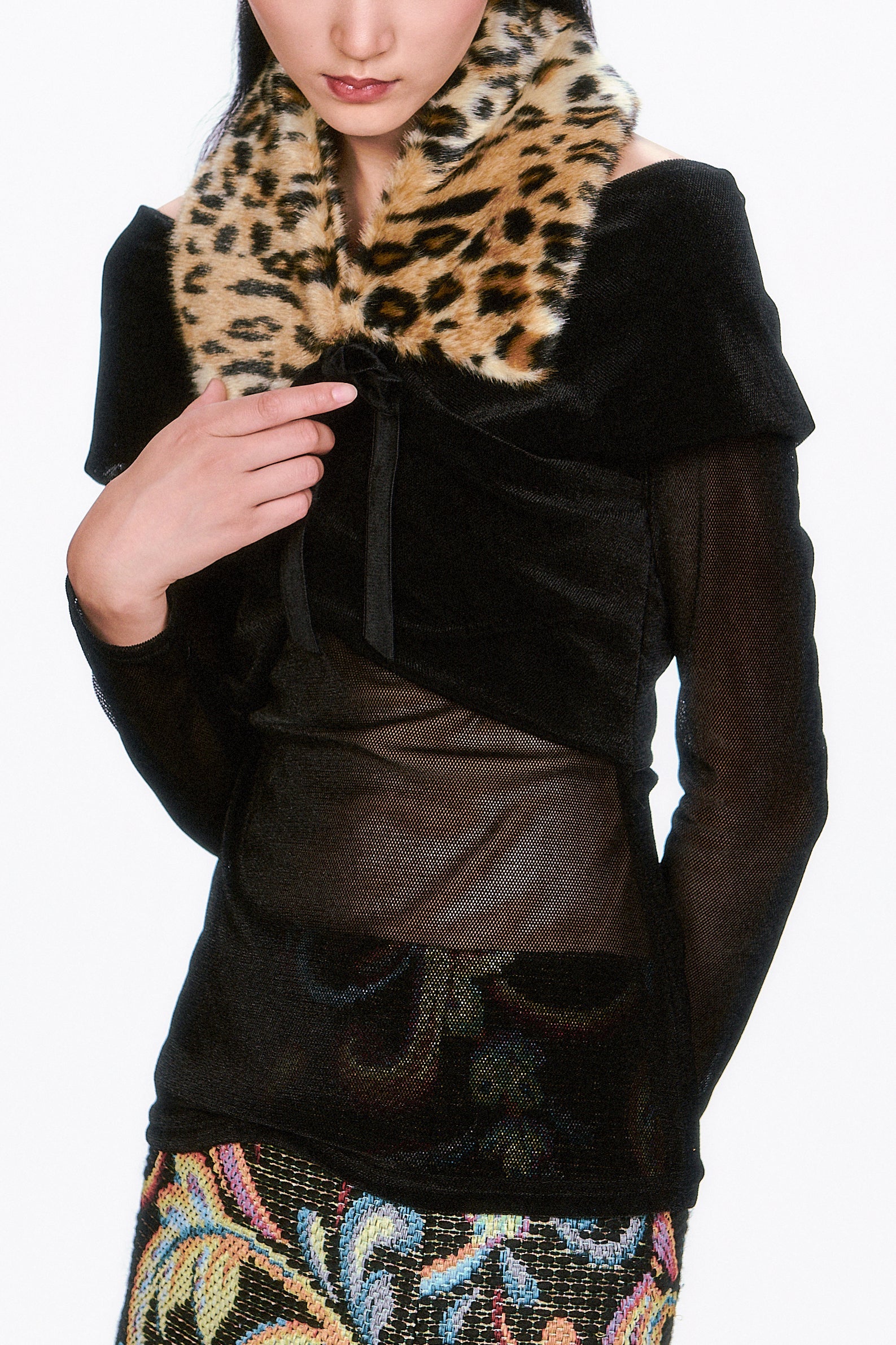 Woman wearing a black coat with a Faux Leopard V-cut Collar, large flaps, tied with black ribbon.