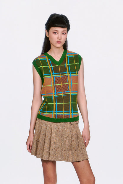 Woman wearing a Plaid Sweater Vest - Leaf Green top and beige pleated skirt