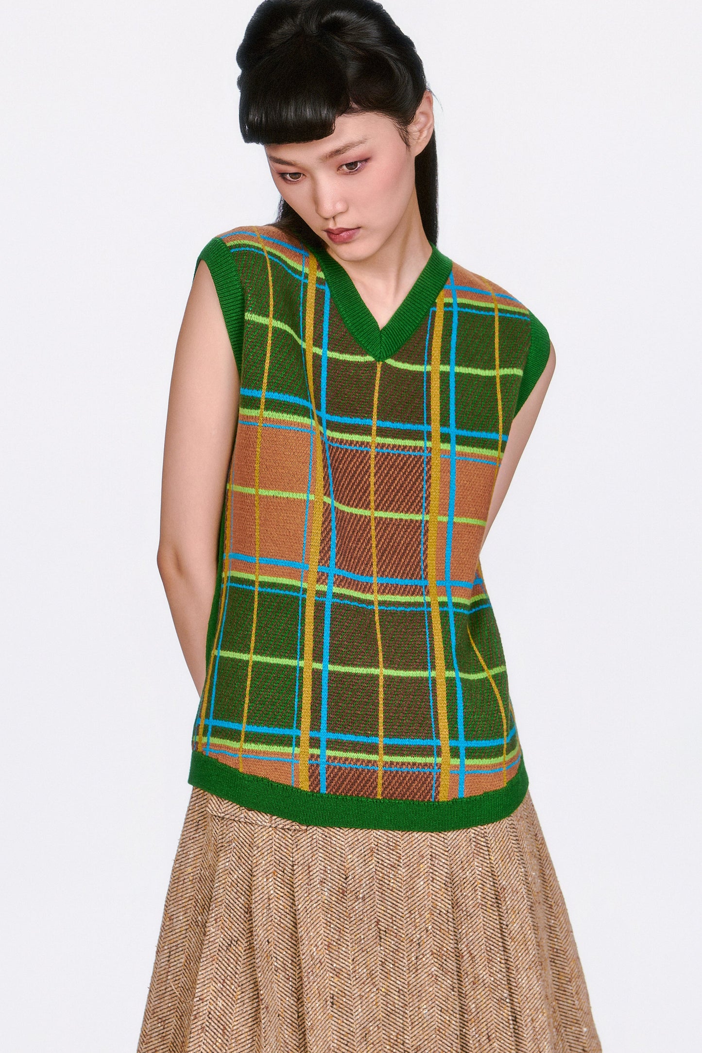 A woman wearing The Herringbone Pleated Skirt Caramel mid-tight high, green top. 