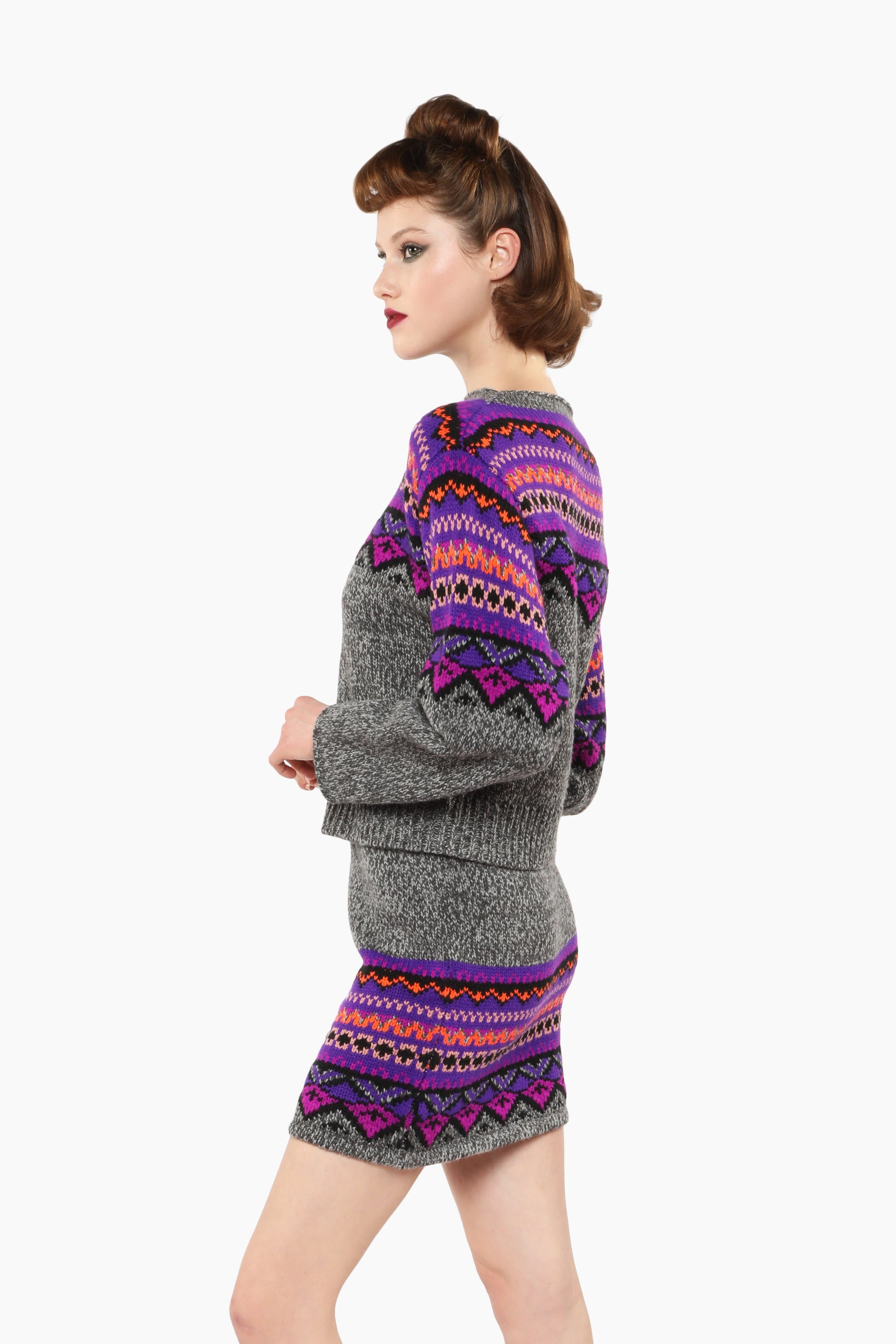Woman wearing Fair Isle Sweater – Magenta and matching skirt set with knee-high boots.