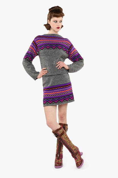 Woman wearing Fair Isle Sweater – Magenta and matching skirt set with knee-high boots.