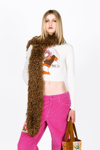Woman wearing a Faux Fur Scarf - Caramel, white crop top with graphic design, and pink pants