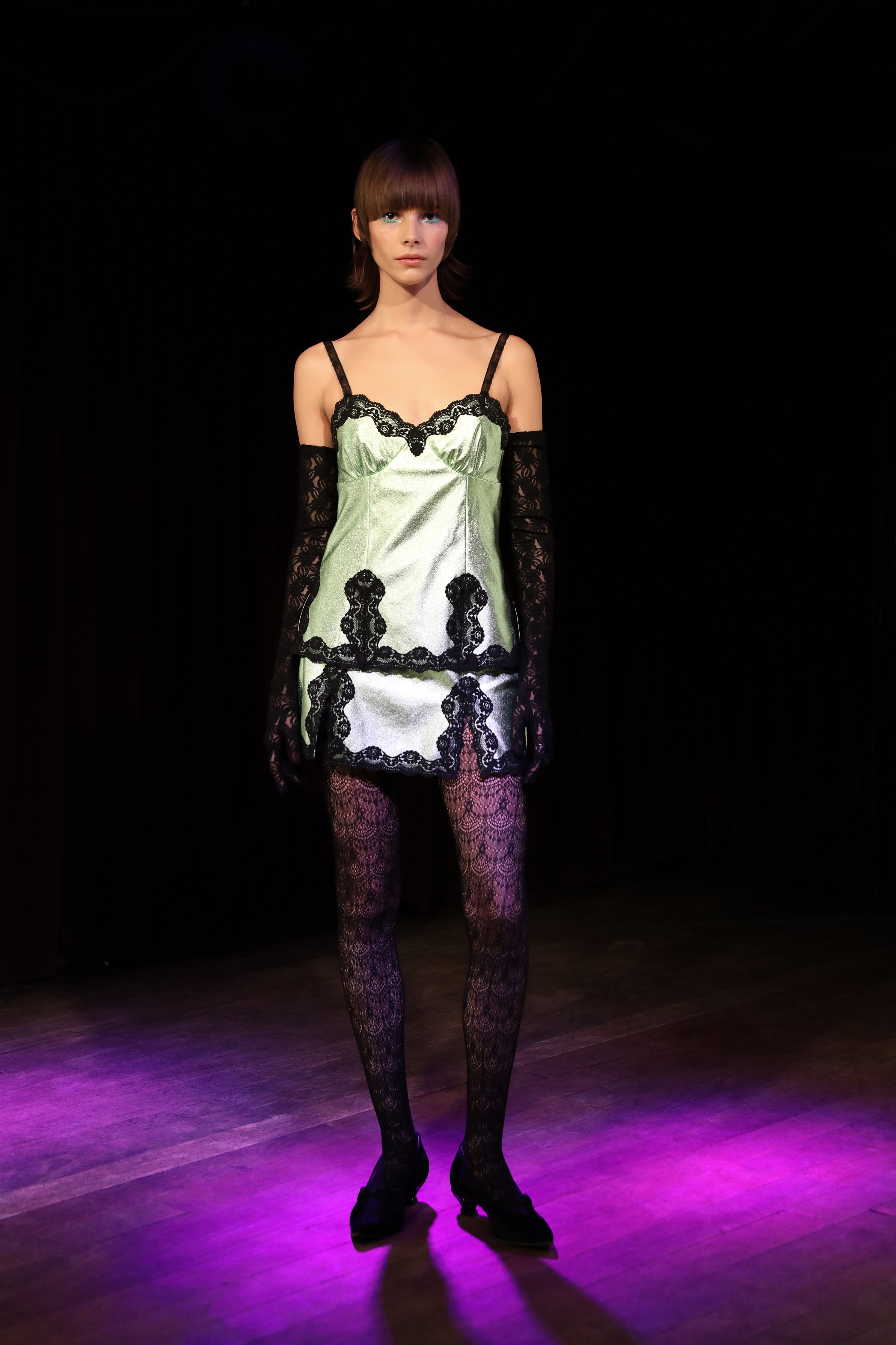 In dimly lit runway for this fashion Anna Sui's Metallic Faux Leather Mini Skirt Peppermint, with black lace top and bottom