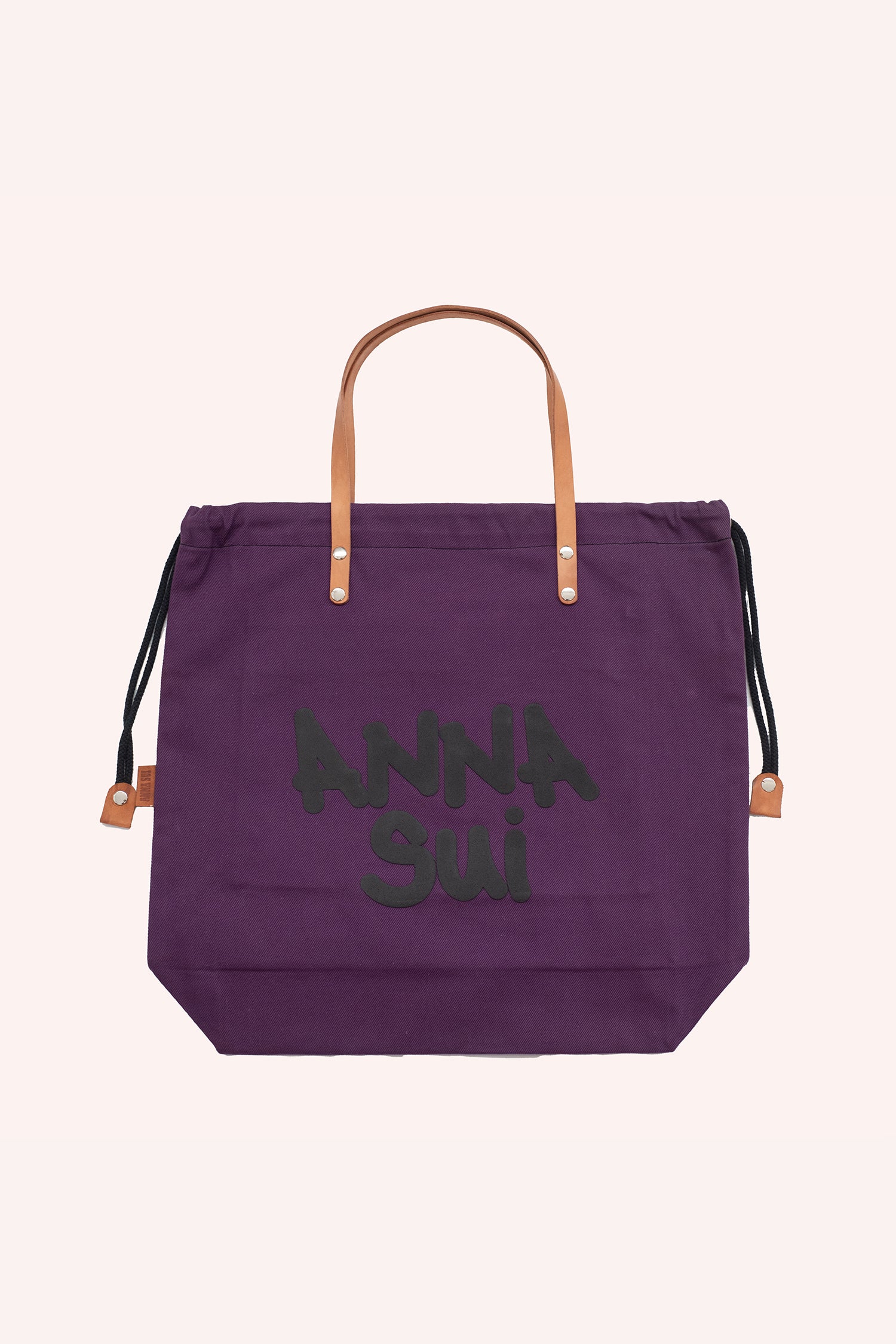 Tote bag, purple squared shape, brown handles, black laces to closed, Anna Sui branding in large font