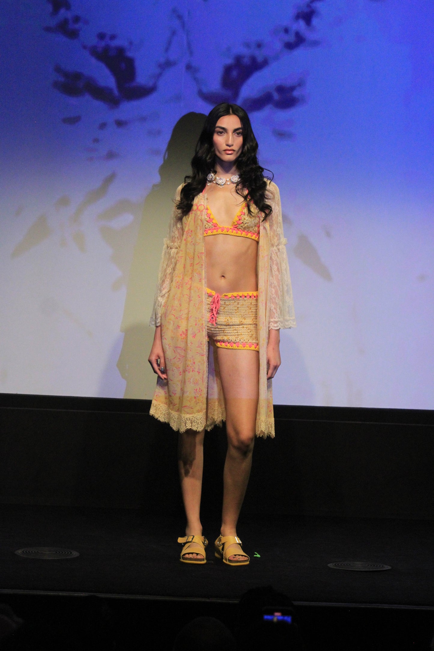 Under runway lights, Arcadia Blossom Lace Cover Up is in yellow color, just above knee, long sleeves