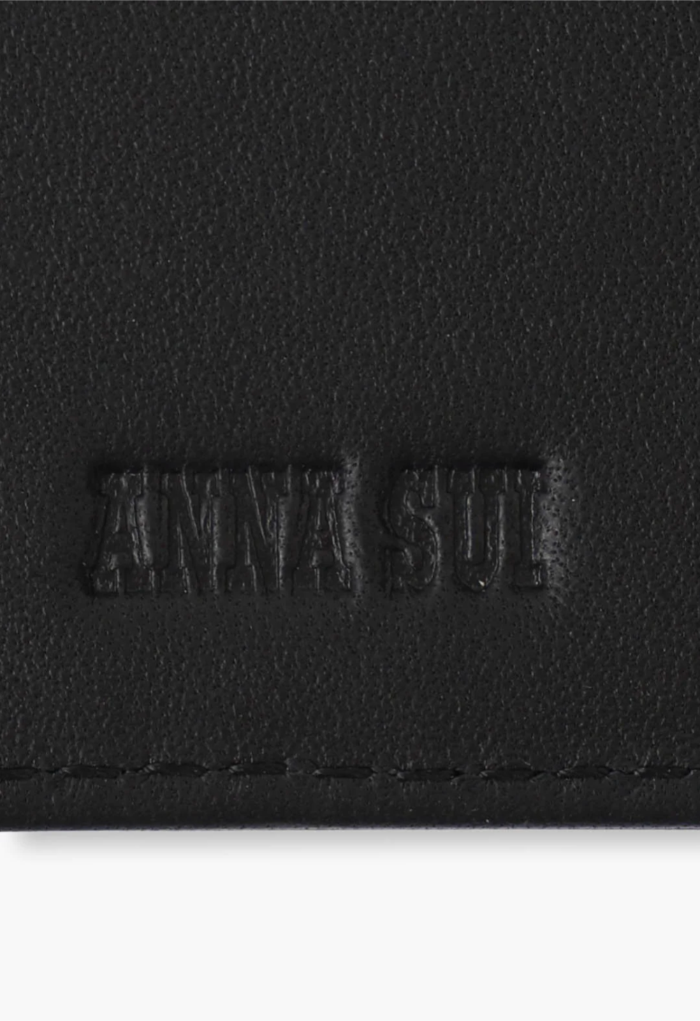 The Roger Wallet in black, detail of the Anna Sui Raised logo and large black stiches