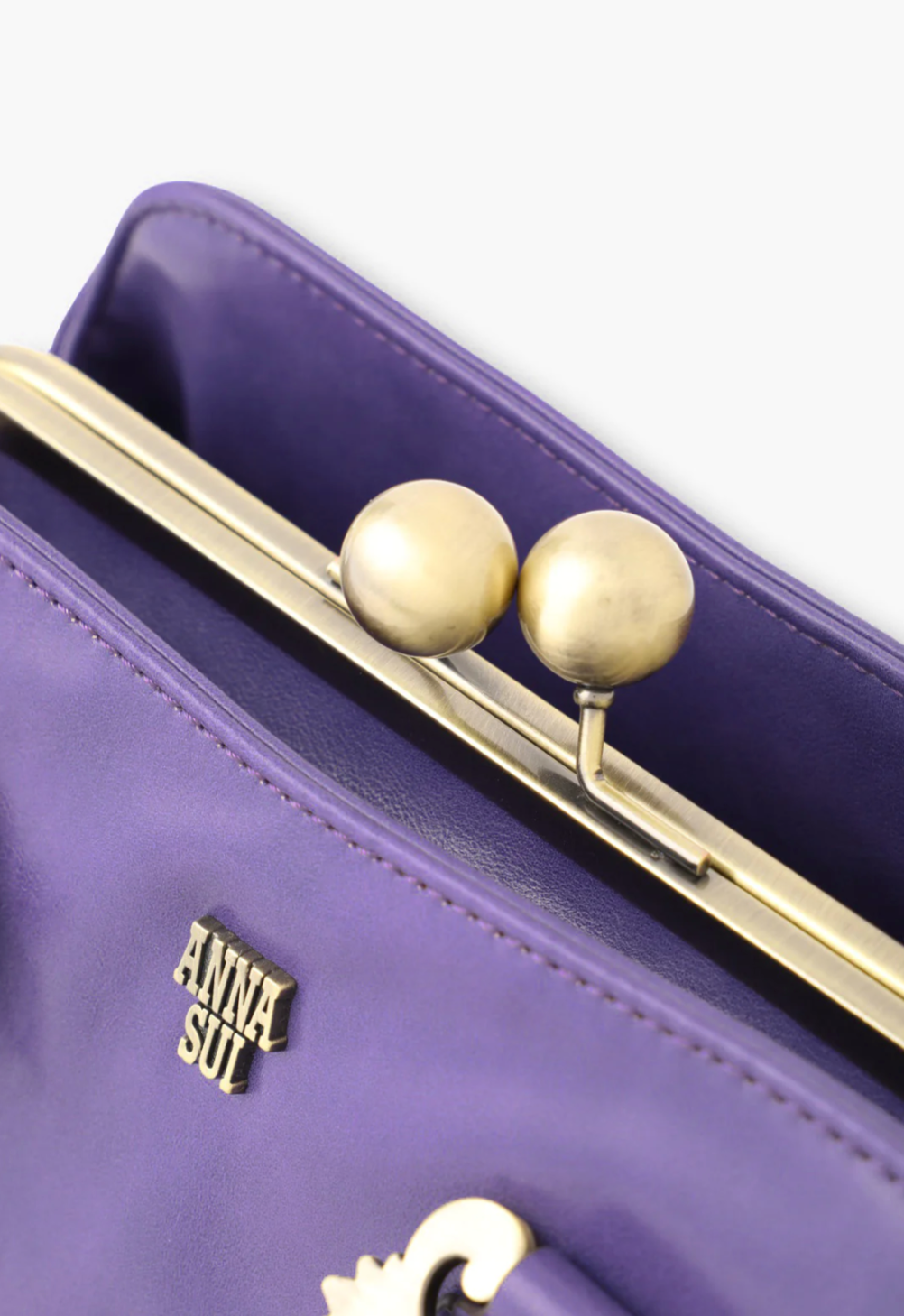 Detail of purple Didion handbag, golden ball clasp closure and frame, Anna Sui golden font label