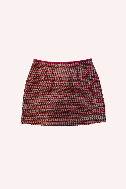 Lurex Tweed Mini Skirt Ruby Multi est une mini-jupe en tweed de couleur rubis, avec une touche de rouge au niveau de l'ourlet supérieur. 