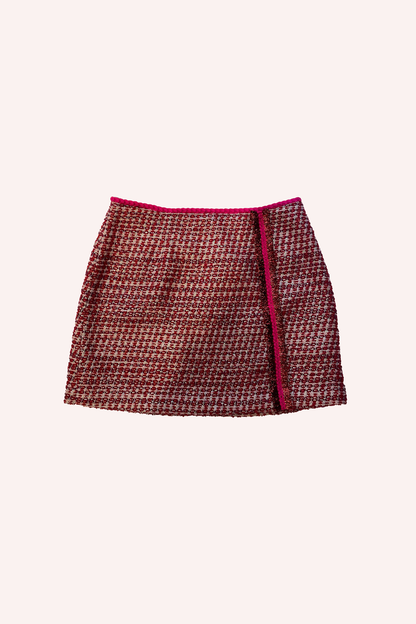 Cette mini-jupe en tweed de couleur rubis, rehaussée de rouge à l'ourlet supérieur et sur le côté gauche, va du haut jusqu'aux hanches.