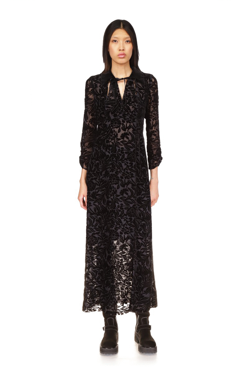 Dress is ankle-length and features a V-cut collar with a lace to fasten it, long sleeves, transparent floral pattern