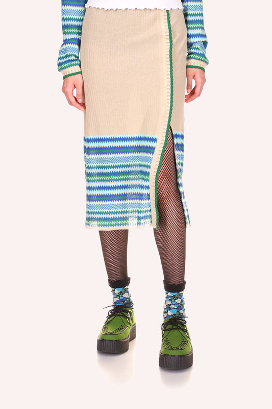 Mid-calf beige skirt, zigzag patterns in hue of green at the bottom, a slit that goes up to mid-thigh