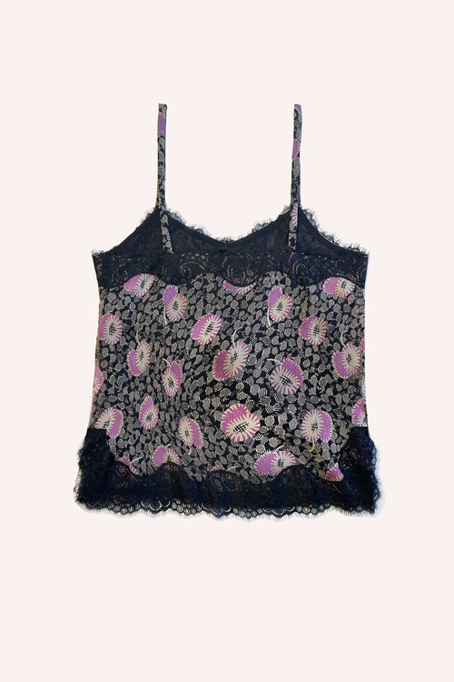 On a black background, white and pink flowers rest on grayish leaves, with black lace stitching accentuating the design
