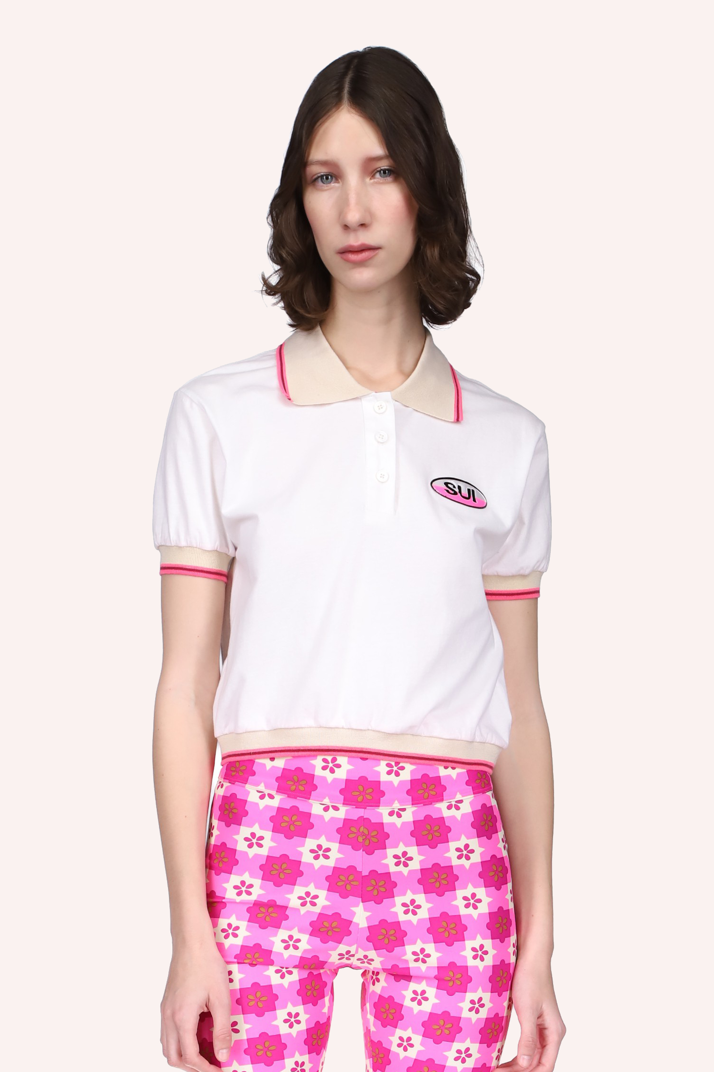 Deco Polo Top Neon Pink, camiseta blanca, costuras con líneas beige y rosa, SUI una etiqueta a la izquierda