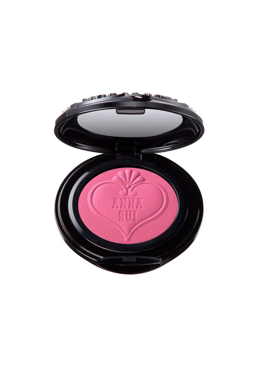 Powder Blush in an open round black container, a mirror into the top lid, a heart-shaped with Anna Sui branding on powder