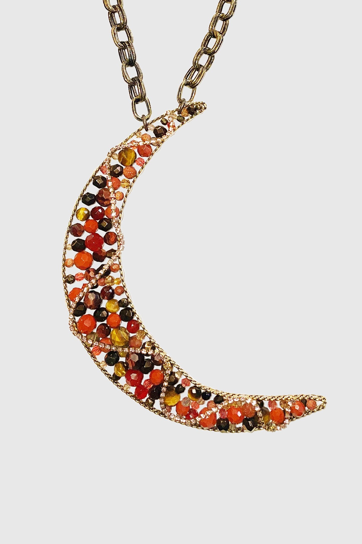 Dandy Girl Moon Necklace, a croissant noon with colored gems and a zigzag golden chain , overall color is orange