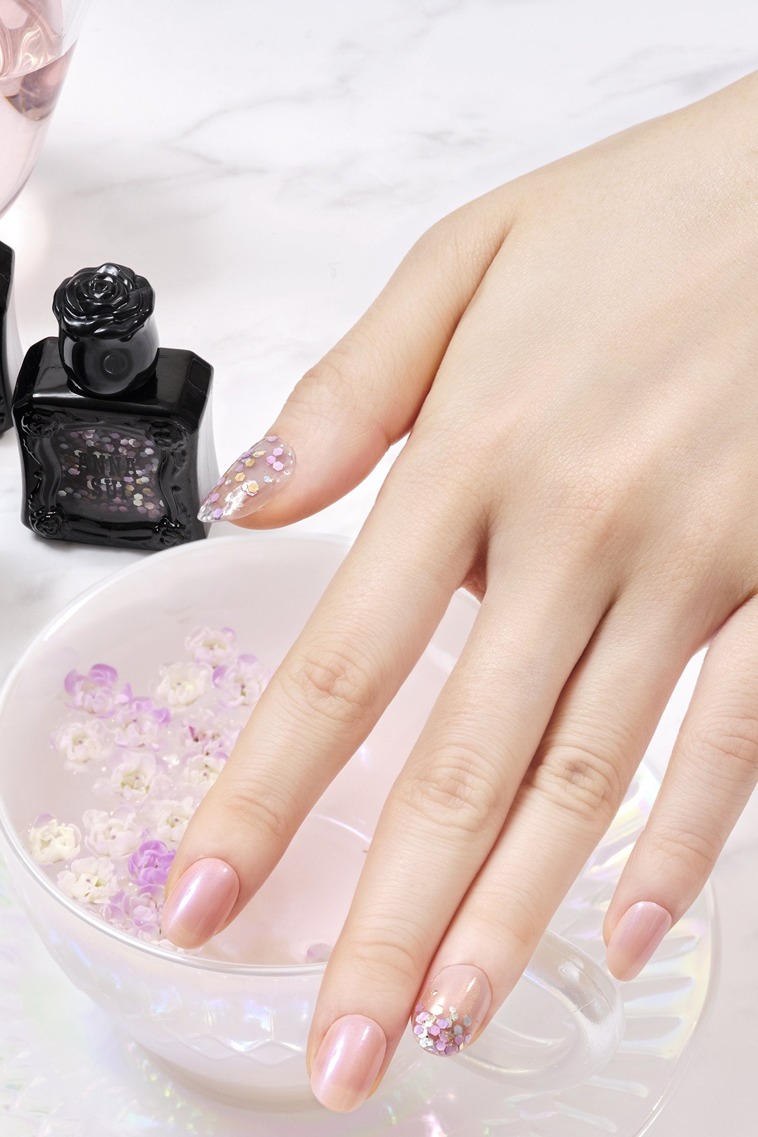 Hand with Nail Polish SHINY PINK with nail topper MERMAID PURPLE, black container with product