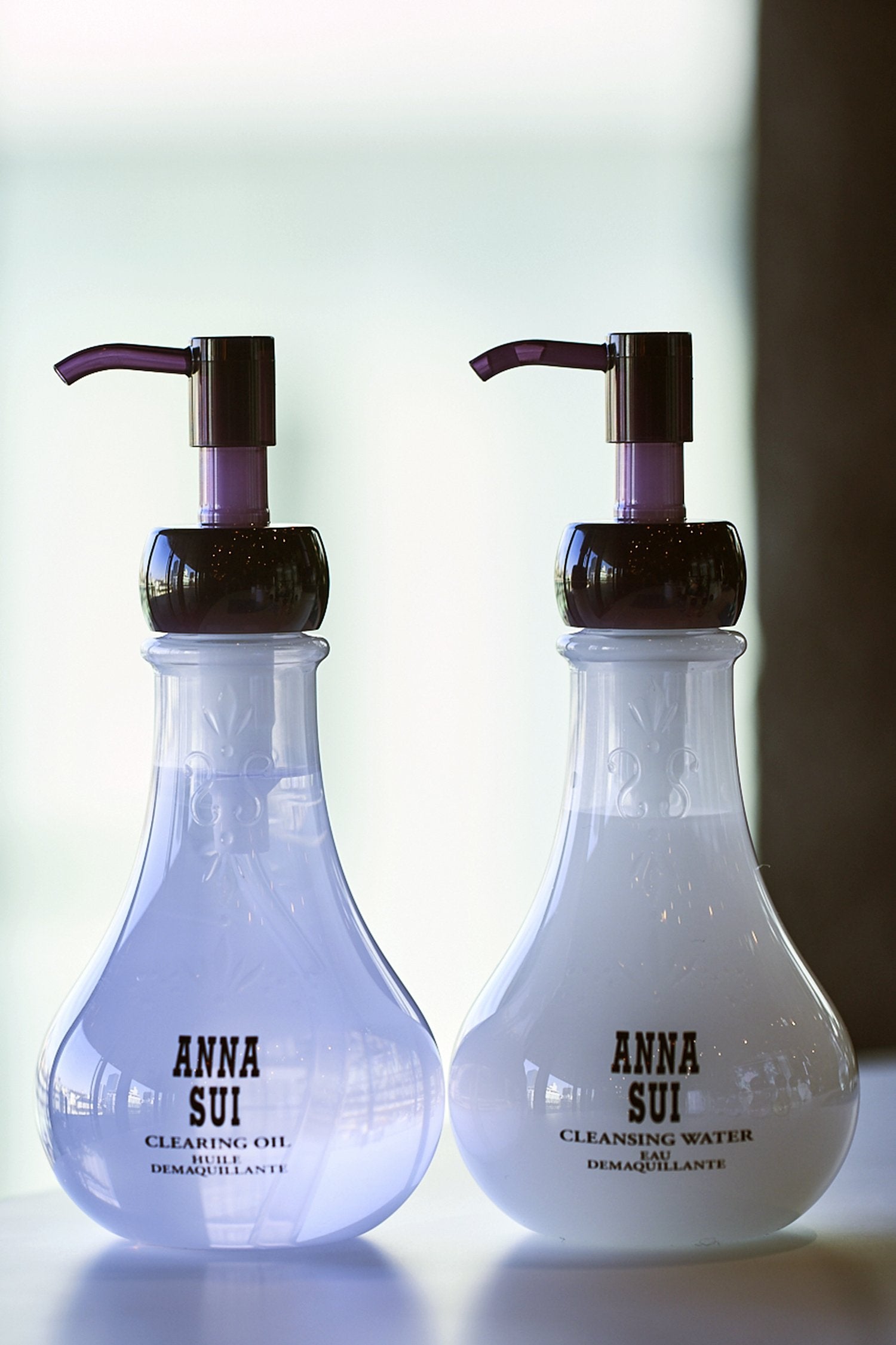 2-bulb-shaped transparent container, floral design and Anna branding, the dispenser is dark purple, 1 water, 1 oil 