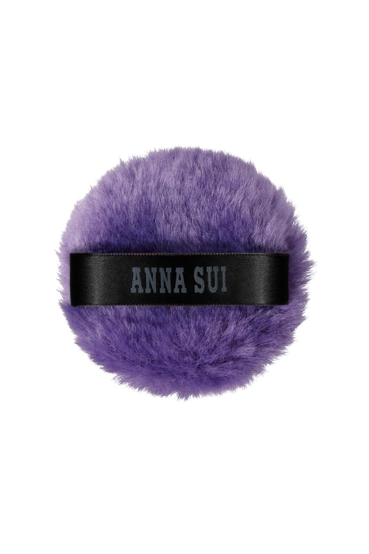 Eine runde, lilafarbene, flauschige Puderquaste mit schwarzer Schleife, mit der Sie Ihre Grundierung für einen Airbrush-Look fixieren können.