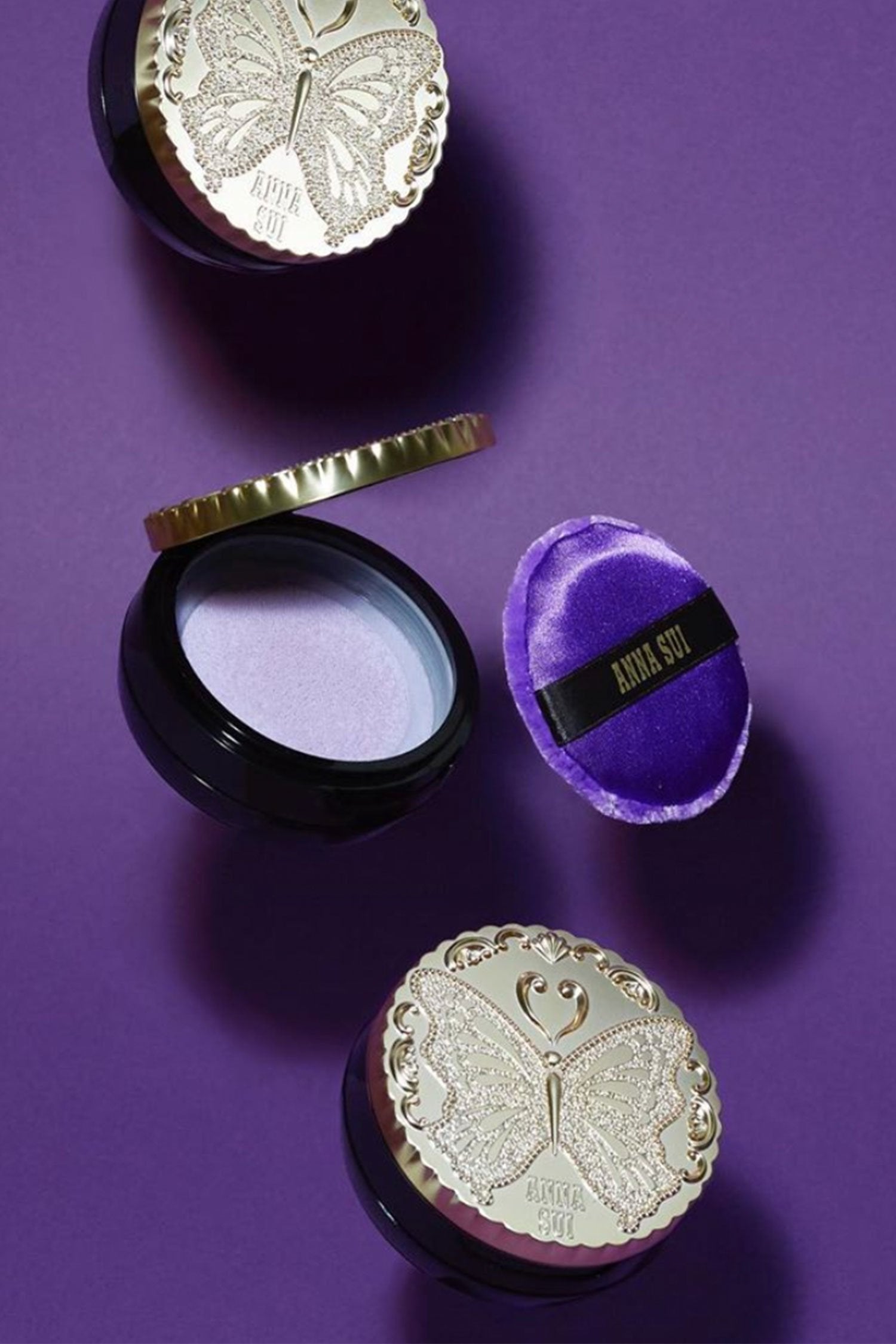 Ensemble of cases, showing a closed Golden lid and black bottom, and open with mirror and purple pad 